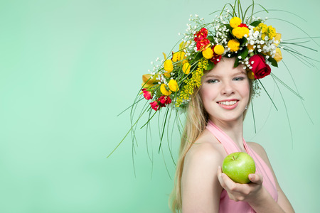 Beautiful young woman with flower wreath and green appleの写真素材
