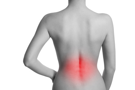 Woman suffering from backache. The lumbar spine is highlighted by red colour.の写真素材