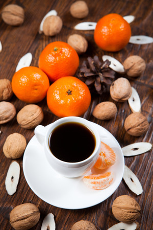 Cup of coffee with tangerines and walnut on old wooden tableの写真素材