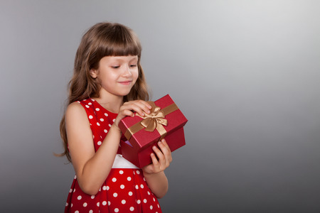 Little girl in vintage spotted red dress holding her presentの写真素材