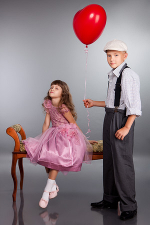 The boy gives a red balloon to the girl. Photo in retro style.の写真素材
