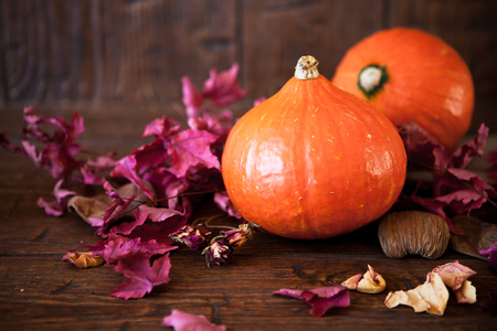 pumpkins with red leaves on old weathered wooden floorの写真素材