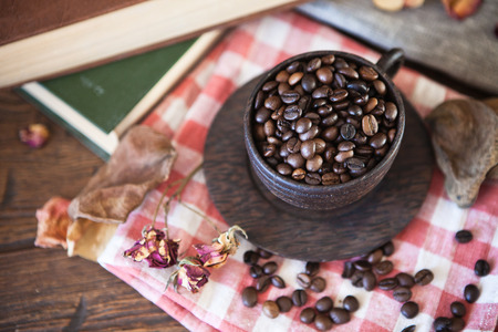 Wooden cup with coffee beans and books on old wooden tableの写真素材