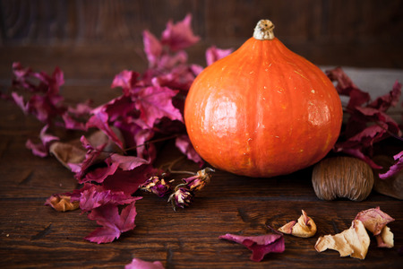 pumpkin with red leaves on old weathered wooden floorの写真素材