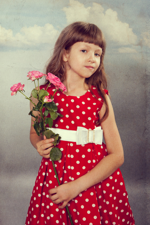 Smiling little girl holding flowers. Closeup. Photo in retro style with old textured paper.の写真素材