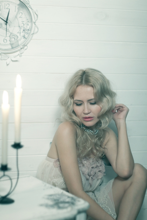 Pretty blonde woman in a white interior. Vintage cold colors with soft effect.の写真素材