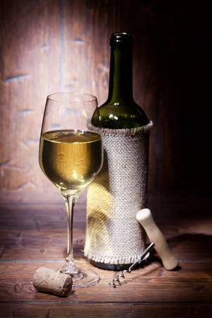 Wine bottles with glass of white wine on old wooden backgroundの写真素材