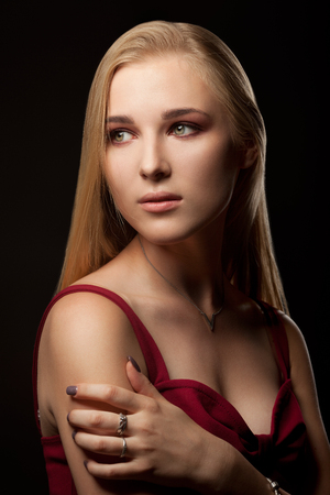 Beautiful tender woman in red dress posing on black backgroundの写真素材