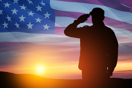 Silhouette of soldier saluting on a background of sunset or sunrise and USA flag. Close-up. Greeting card for Veterans Day, Memorial Day, Independence Day. America celebration.の写真素材