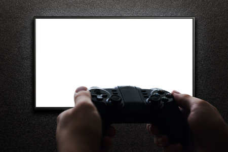 Hand holding gamepad to playing video game on the tv. Blank screen. Mockup.