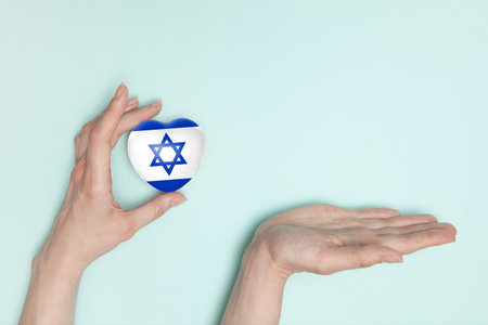Female hands with small heart with print of Israel flag and palm for your offers. Flat lay. Copy space.の写真素材