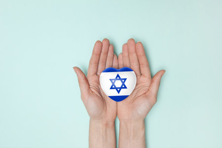 Heart with print of Israel flag in female hands. Flat lay. Copy space.の写真素材