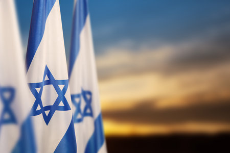 Israel flags with a star of David over cloudy sky background on sunset. Patriotic concept about Israel with national state symbols. Banner with place for text.の写真素材
