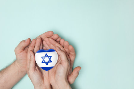 Heart with print of Israel flag in female and male hands. Flat lay. Copy space.の写真素材