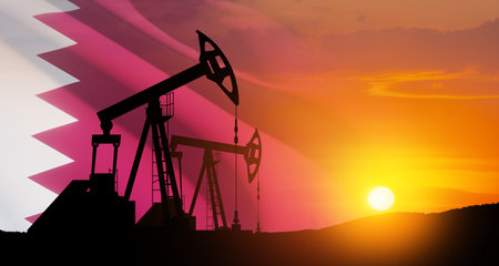 Oil drilling derricks at desert oilfield with Qatar flag. The change in oil prices caused by the war. Oil prices are rising because of the global crisis. Crude oil production from the ground.の写真素材
