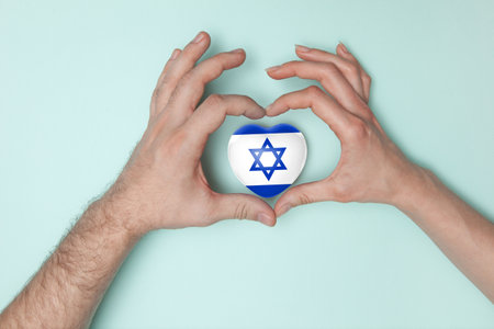 Heart with print of Israel flag in female and male hands.. Flat lay. Copy space.の写真素材