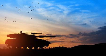 Silhouette of army tank at sunset sky background. Military machinery.の写真素材