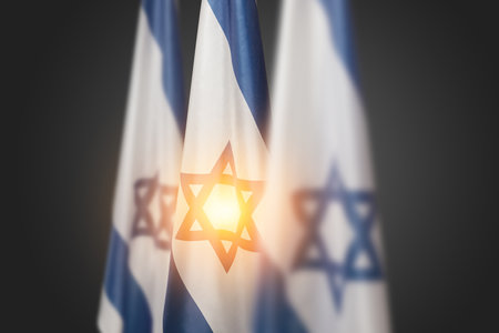 Israel flags with a star of David over dark gray background. Patriotic concept about Israel with national state symbols. Banner with place for text.の写真素材