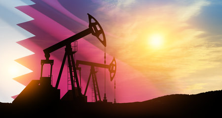 Oil drilling derricks at desert oilfield with Qatar flag. The change in oil prices caused by the war. Oil prices are rising because of the global crisis. Crude oil production from the ground.の写真素材