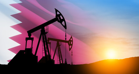 Oil drilling derricks at desert oilfield with Qatar flag. The change in oil prices caused by the war. Oil prices are rising because of the global crisis. Crude oil production from the ground.の写真素材