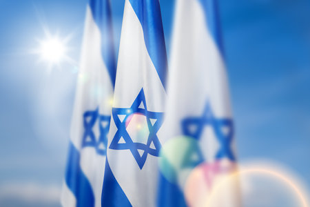 Israel flags with a star of David over cloudy sky background. Patriotic concept about Israel with national state symbols. Banner with place for text.の写真素材