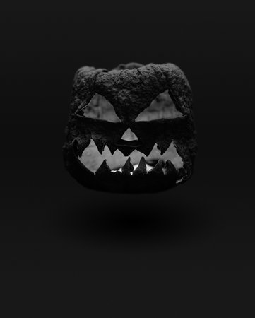 Black dry halloween pumpkin smile and scary eyes for party night. Close up view of scary Halloween pumpkin with eyes glowing on black background poster. Selective focus.の写真素材