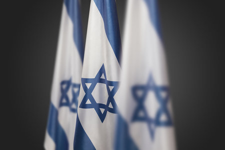 Israel flags with a star of David over dark gray background. Patriotic concept about Israel with national state symbols. Banner with place for text.の写真素材