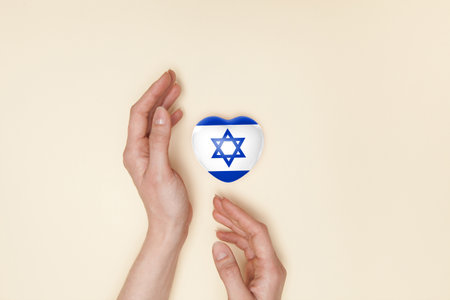 Heart with print of Israel flag in female hands. Flat lay. Copy space.の写真素材