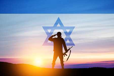 Silhouette of soldier saluting against the sunrise in the desert and Israel flag.の写真素材