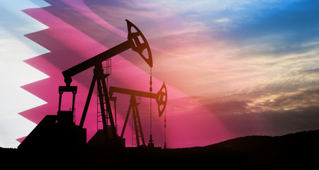 Oil drilling derricks at desert oilfield with Qatar flag. The change in oil prices caused by the war. Oil prices are rising because of the global crisis. Crude oil production from the ground.の写真素材