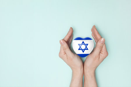 Heart with print of Israel flag in female hands. Flat lay. Copy space.の写真素材