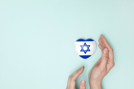 Heart with print of Israel flag in female hands. Flat lay. Copy space.の写真素材