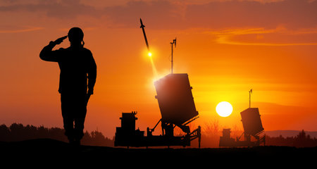 Israel's Iron Dome air defense missile launches. Silhouettes of soldier and Israel's Iron Dome air defense. The missiles are aimed at the sky at sunset. Missile defense.の写真素材