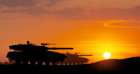 Silhouettes of army tanks at sunset sky background. Military machinery.の写真素材