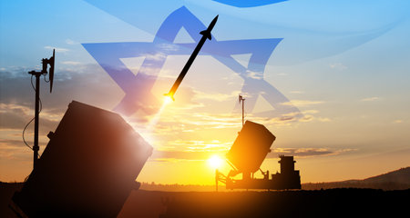 Closeup of Israel's Iron Dome air defense missile launches. The missiles are aimed at the sky at sunset with Israel flag. Missile defense, a system of salvo fire.の写真素材