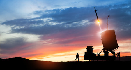 Israel's Iron Dome air defense missile launches. Silhouettes of soldier and Israel's Iron Dome air defense. The missiles are aimed at the sky at sunset. Missile defense.の写真素材