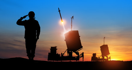 Israel's Iron Dome air defense missile launches. Silhouettes of soldier and Israel's Iron Dome air defense. The missiles are aimed at the sky at sunset. Missile defense.の写真素材