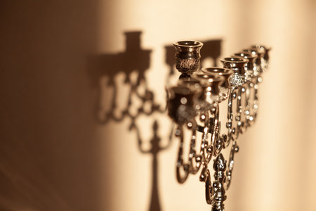 Hanukkah menorah, or hanukkiah in the light of the sun at sunset for Jewish holiday Hanukkah. Hanukkah lamp, nine-branched candelabrum without candles with a shadow on the wall.の写真素材