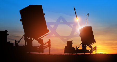Israel's Iron Dome air defense missile launches. The missiles are aimed at the sky at sunset with Israel flag. Missile defense, a system of salvo fire.の写真素材