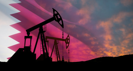Oil drilling derricks at desert oilfield with Qatar flag. The change in oil prices caused by the war. Oil prices are rising because of the global crisis. Crude oil production from the ground.の写真素材