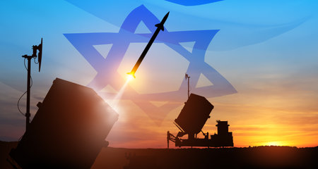 Closeup of Israel's Iron Dome air defense missile launches. The missiles are aimed at the sky at sunset with Israel flag. Missile defense, a system of salvo fire.の写真素材