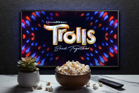 Trolls Band Together trailer or movie on TV screen. TV with remote control, popcorn bowl and home...