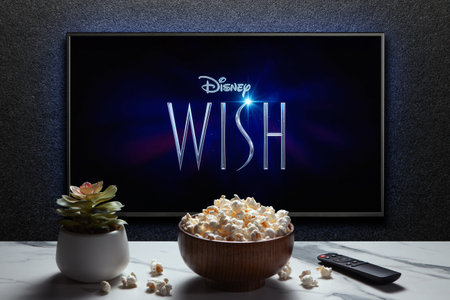 Wish trailer or movie on TV screen. TV with remote control, popcorn bowl and home plant. Astana, Kazakhstan - November 15, 2023.のeditorial素材