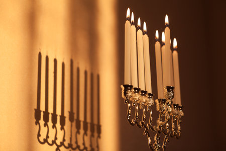 Closeup of Hanukkah menorah, or hanukkiah in the light of the sun at sunset for Jewish holiday Hanukkah. Hanukkah lamp, nine-branched candelabrum with burning candles with a shadow on the wall.の写真素材