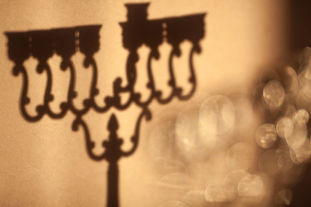 Shadow of Hanukkah menorah, or hanukkiah. Jewish holiday Hanukkah background. Shadow of Hanukkah lamp, nine-branched candelabrum without candles is out of focus. Selective focus.の写真素材