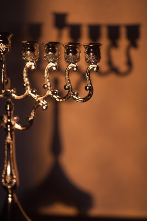Closeup of Hanukkah menorah, or hanukkiah in the light of the sun at sunset for Jewish holiday Hanukkah. Hanukkah lamp, nine-branched candelabrum without candles with a shadow on the wall.の写真素材