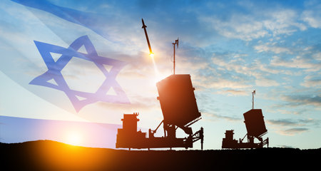 Israel's Iron Dome air defense missile launches. The missiles are aimed at the sky at sunset with Israel flag. Missile defense, a system of salvo fire.の写真素材