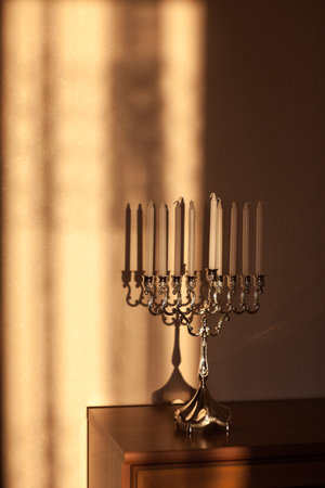 Hanukkah menorah, or hanukkiah in the light of the sun at sunset for Jewish holiday Hanukkah. Hanukkah lamp, nine-branched candelabrum with candles with a shadow on the wall.の写真素材