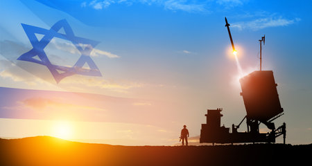 Israel's Iron Dome air defense missile launches. Silhouettes of soldier and Israel's Iron Dome air defense. The missiles are aimed at the sky at sunset with Israel flag. Missile defense.の写真素材