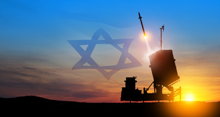 Israel's Iron Dome air defense missile launches. The missiles are aimed at the sky at sunset with Israel flag. Missile defense, a system of salvo fire.の写真素材